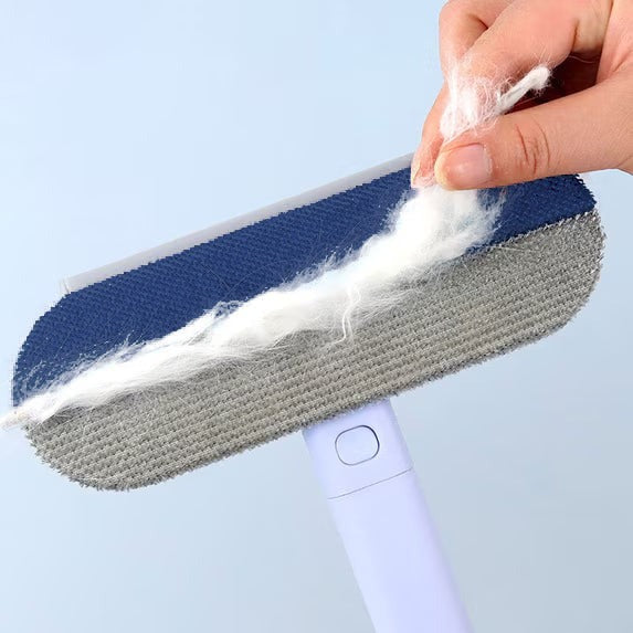 A hand peeling a strip of white pet fur off the Fur Paddle's navy pad